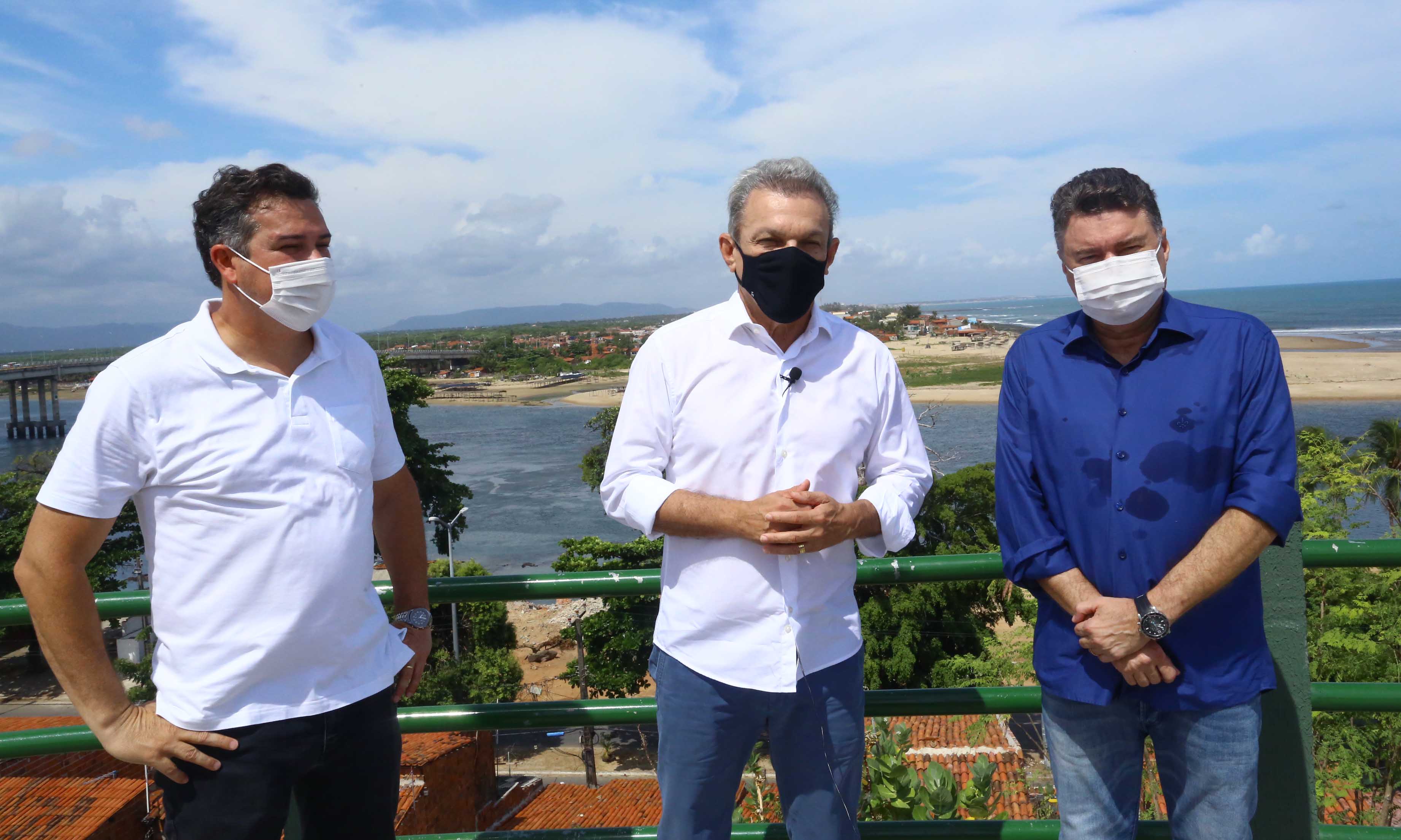 Três pessoas com máscara, paradas em um mirante que mostra o rio ceará ao fundo